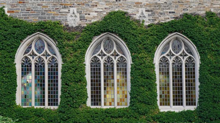 Stone building with stained glass windows, covered in ivy