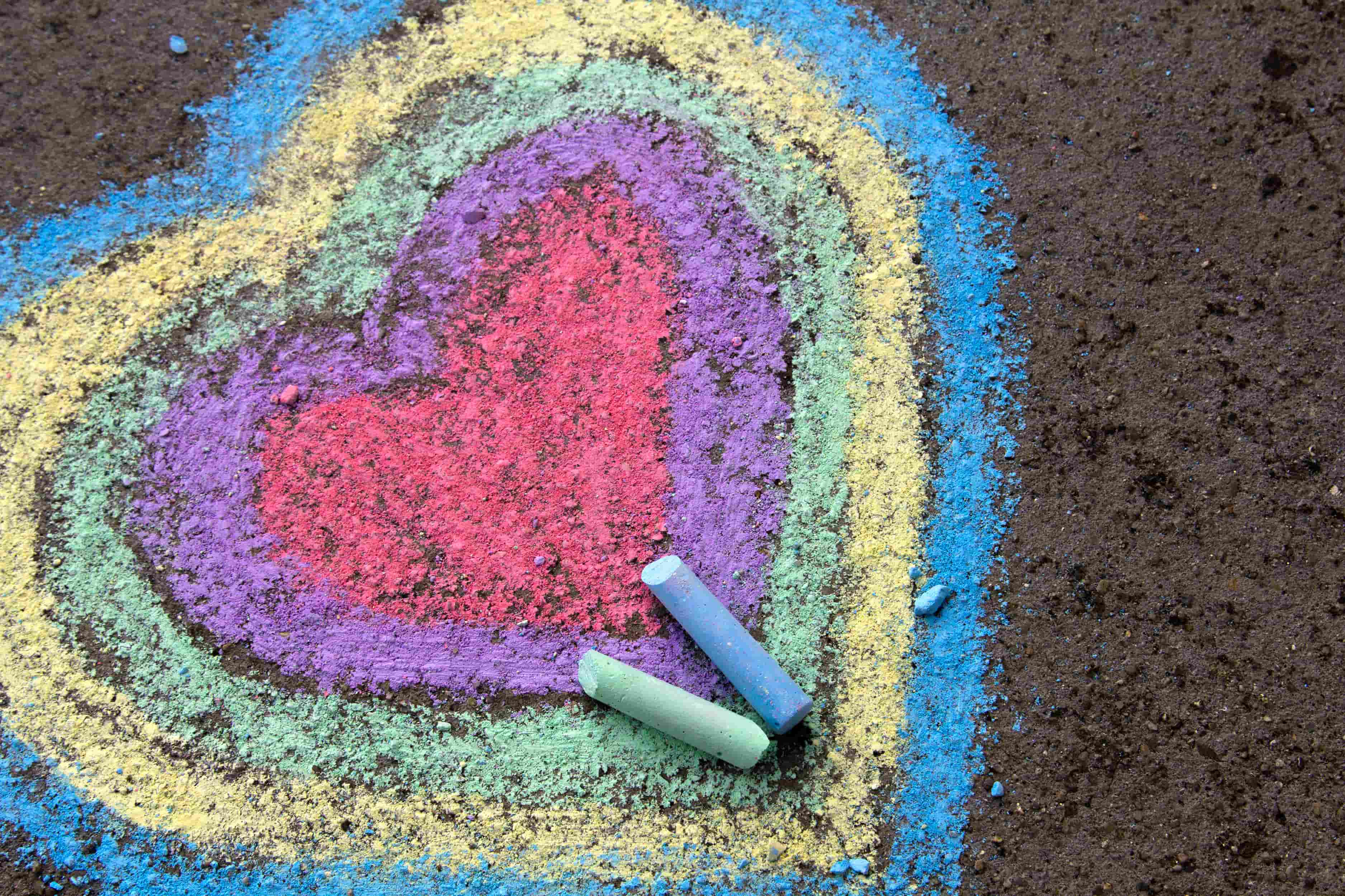 Concentric hearts drawn on sidewalk with red, purple, green, yellow, and blue chalk