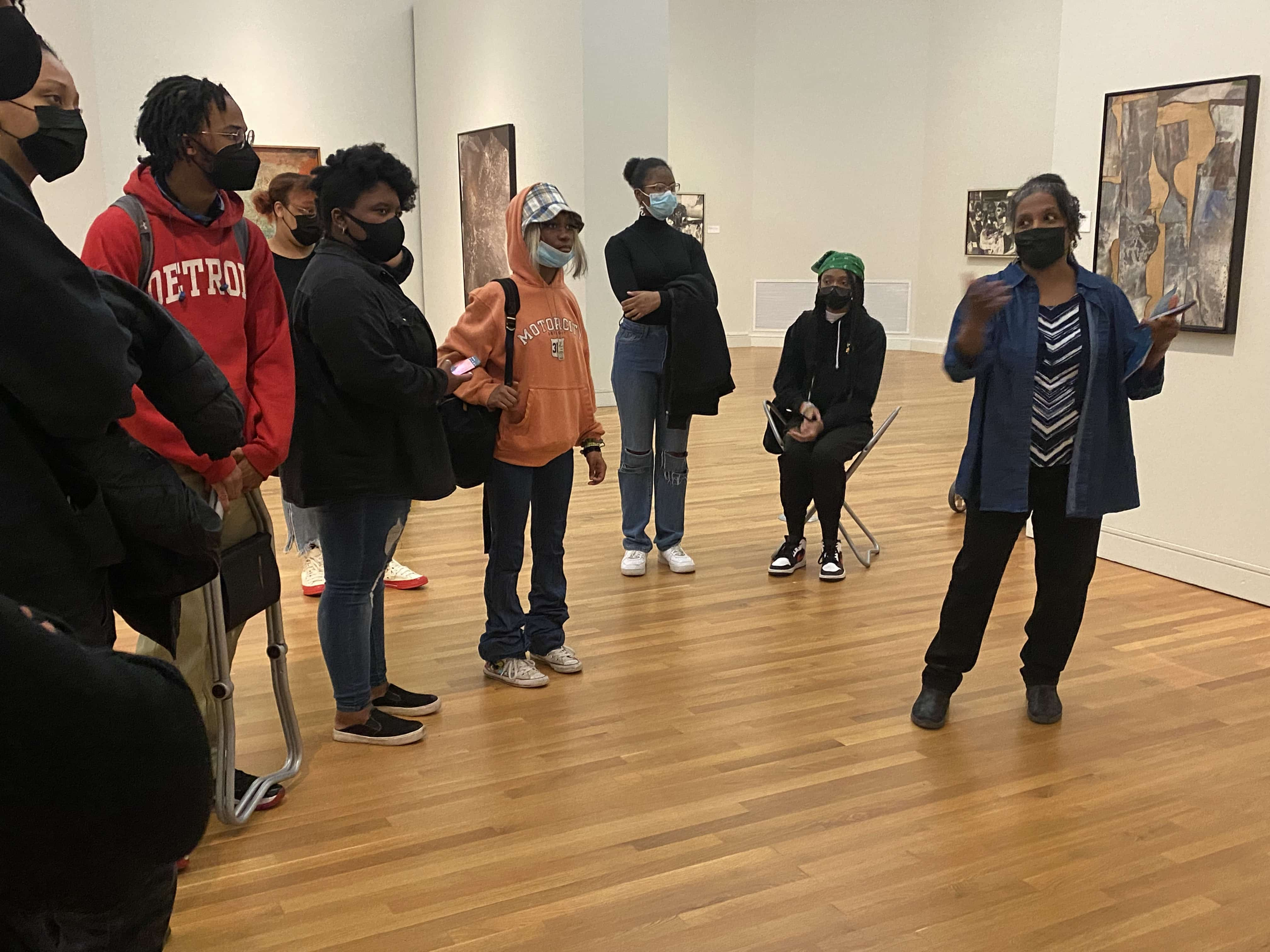 Patrons wearing masks in discussion beside a wall of art.