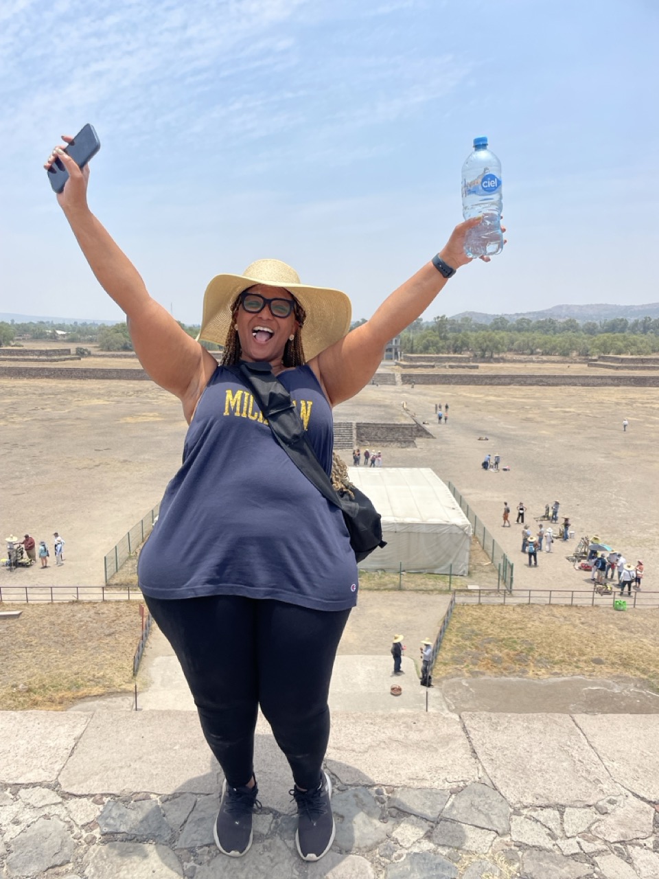 Robyn stands at the top of the pyramids of Teotihuacan with her hands up in the air as a celebration of climbing to the top.