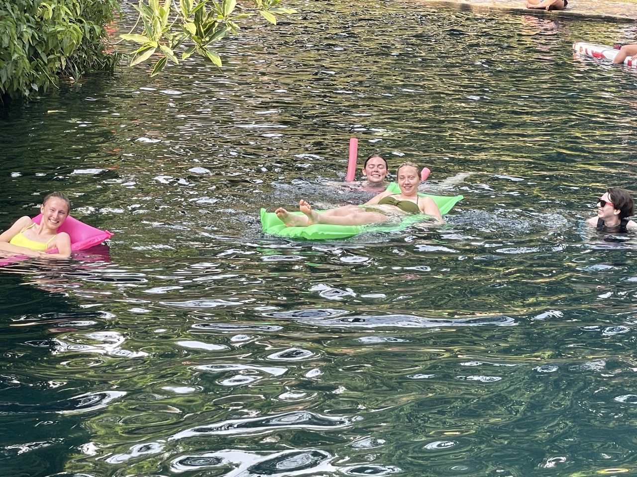 Four interns float down the river at Las Estacas Eco-park. Two lie on inflatables while the other two swim at their side.