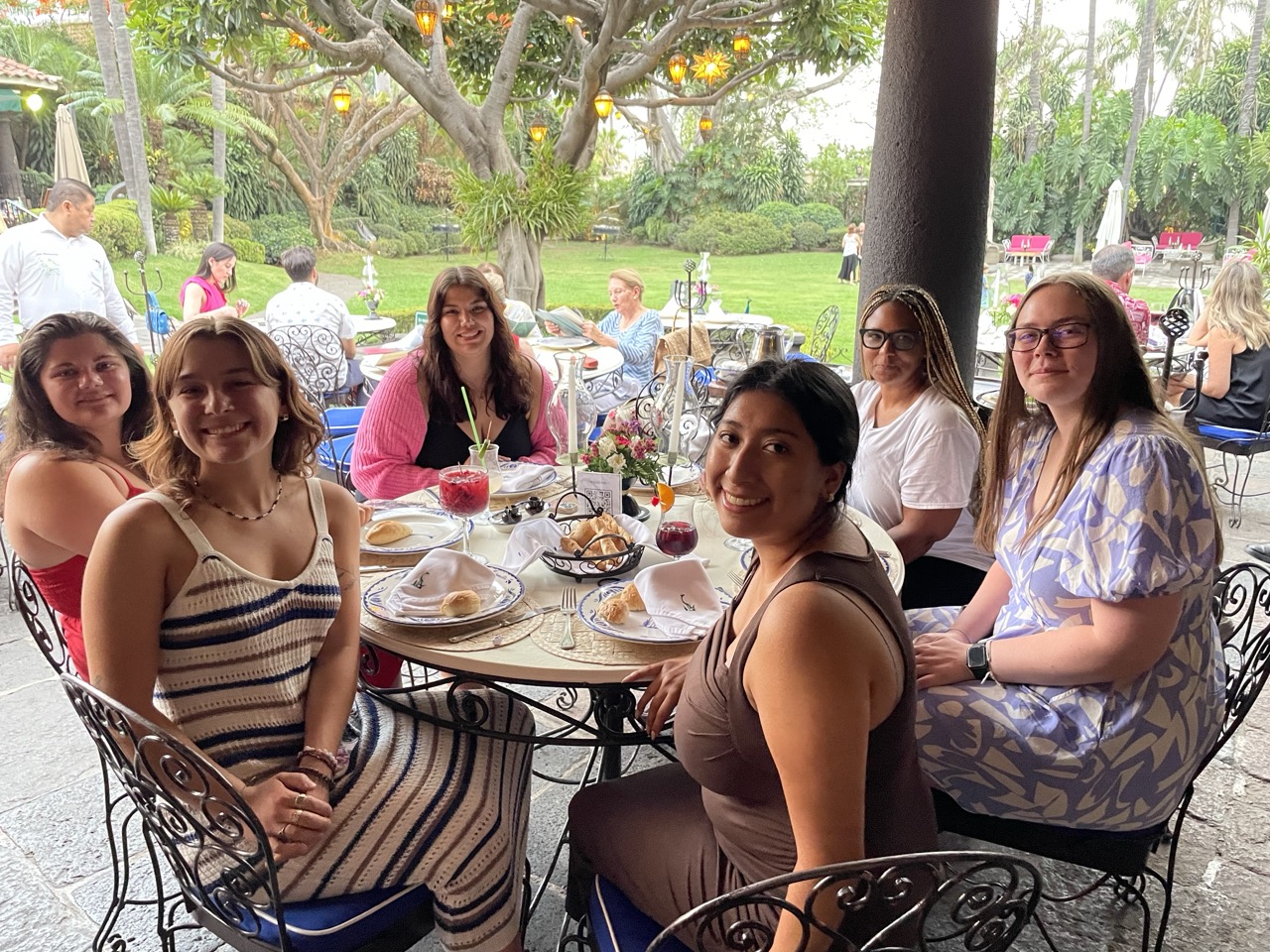 Five interns turn to face the camera and smile as they sit at a dinner table at Las Mananitas restaurant in Cuernavaca, Mexico.