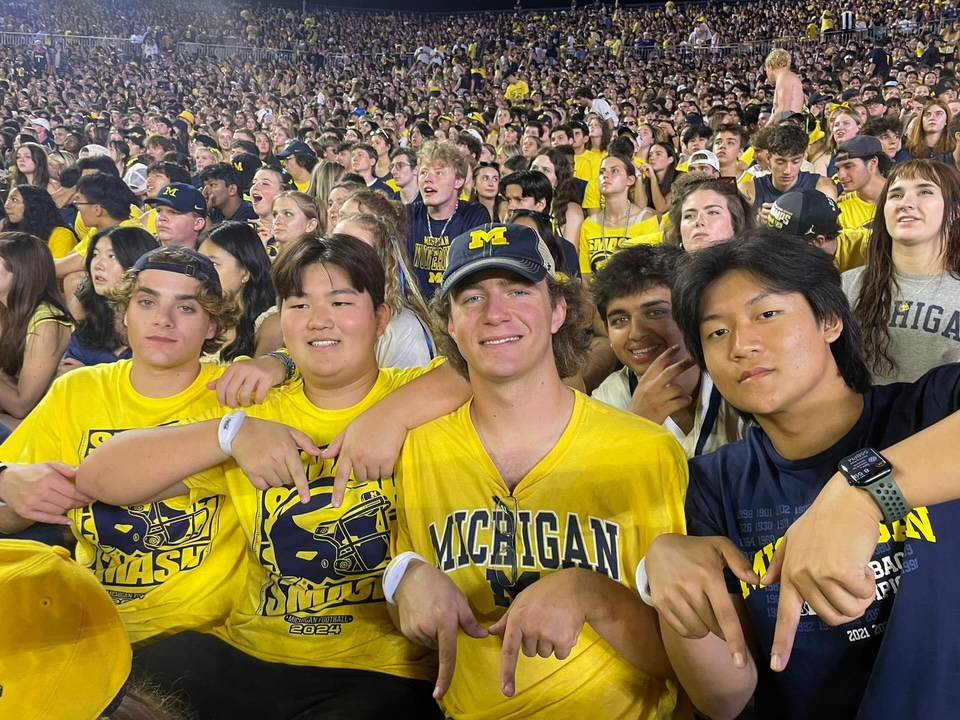 Four LEAPS students create the Block M with their hands while watching a U-M football game