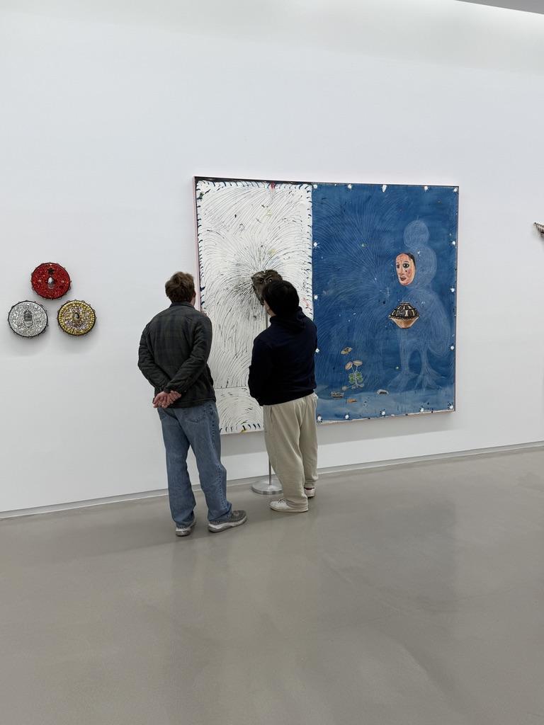 Two students look at a large painting. 
