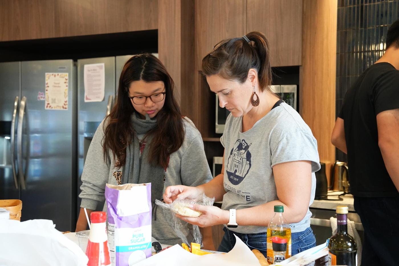 Two women cook together in a kitchenette. 