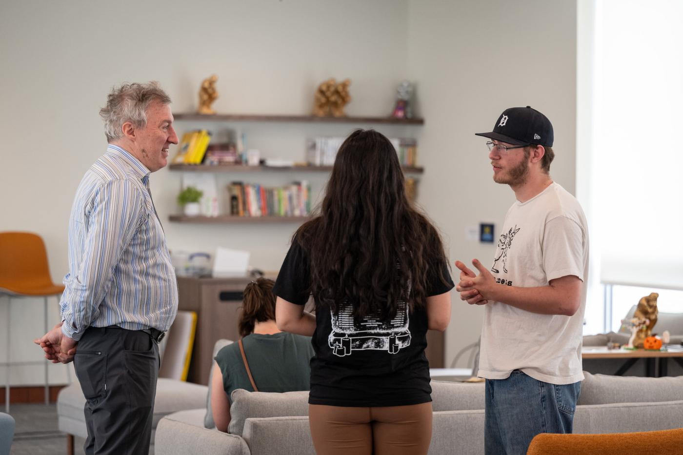 Two students talk to a community member in the Florent Gillet common room. 