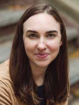 Headshot of adult smiling calmly, outdoors.