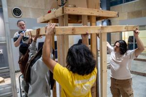 LEAPS students hold wood planks and use tools to create the layered altar called an ofrenda 