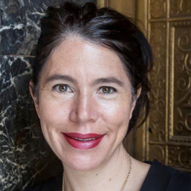 Headshot of adult wearing striking red lipstick, smiling.