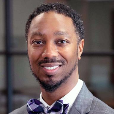 Headshot of adult wearing a purple bowtie, smiling.