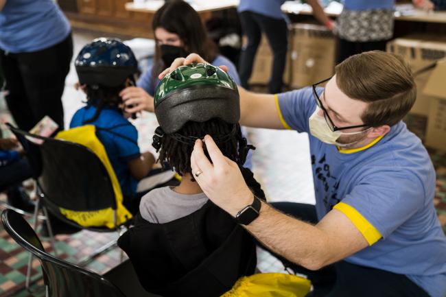 Volunteer fitting child with bike helmet