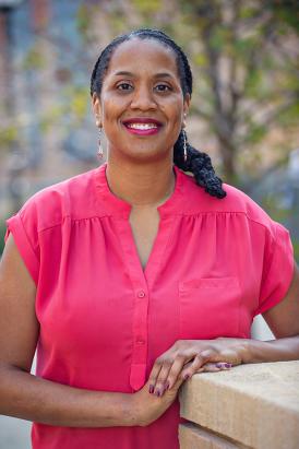 Dr. Camille Wilson, wearing a bright pink top, smiles into the camera