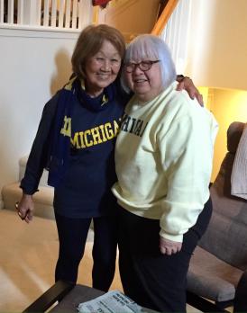 Photo of Jeanette Lim Esbrook with Lida Lim. Esbrook's arm is around Lim's shoulders. Both wear University of Michigan sweatshirts. 