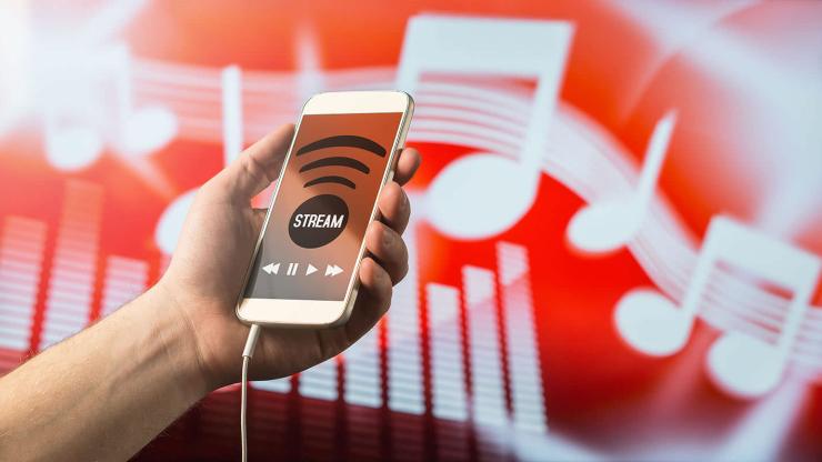 A hand holds a cell phone showing a streaming app
