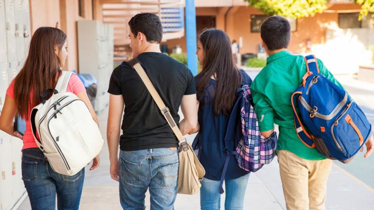 four high school students walking with backpacks to class
