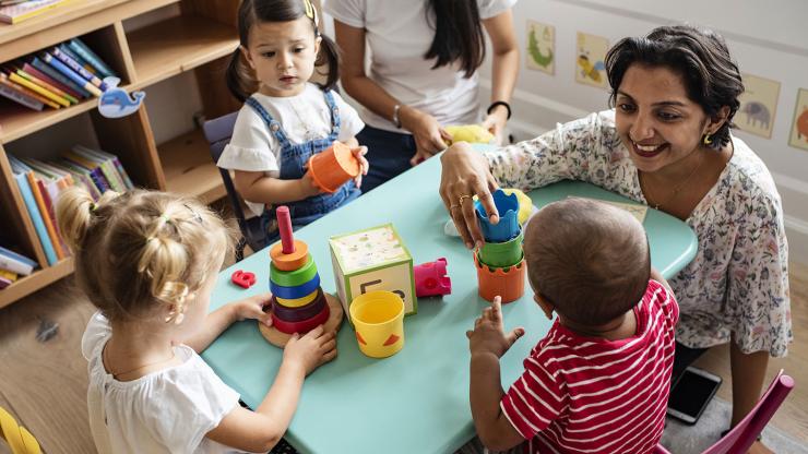 Children at a table arrange blocks with a teacher