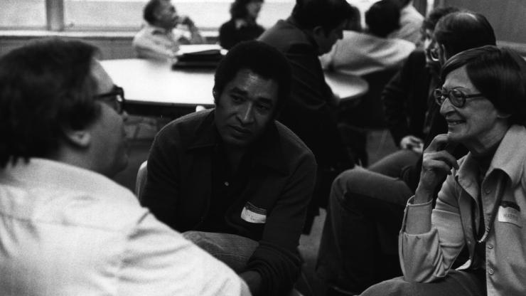 Black and white photo of Don Harrison in conversation with two others