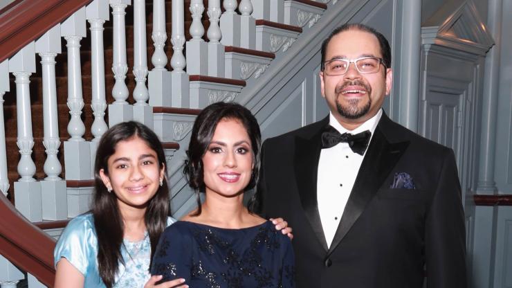 Dr. Ruby Siddiqui and her family, in dress attire, smile and pose for a photo in front of a staircase.