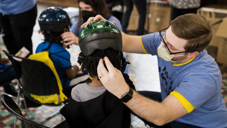 Volunteer fitting child with bike helmet