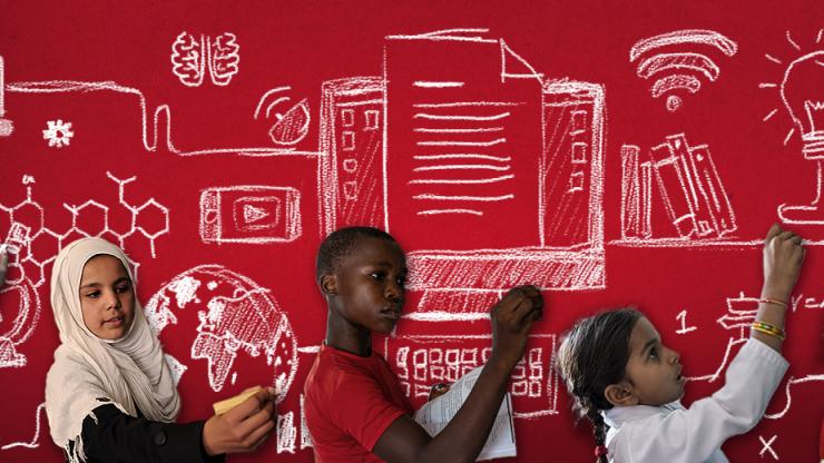 Children sketching ideas on a red wall. 