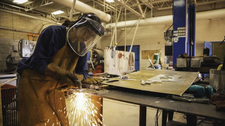 Teenage woman welding in a classroom