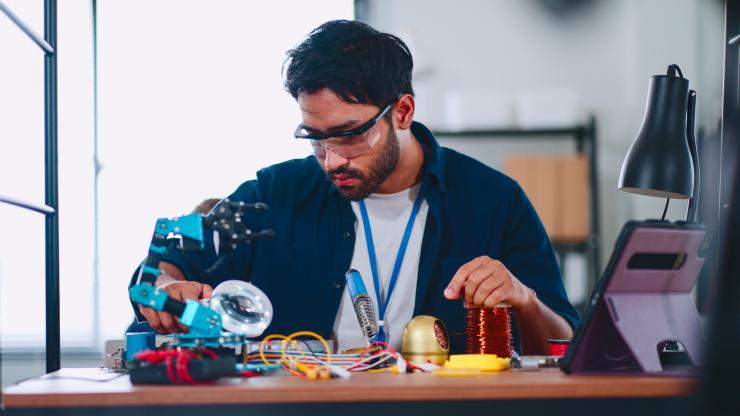 A student practicing electrical work at a desk.