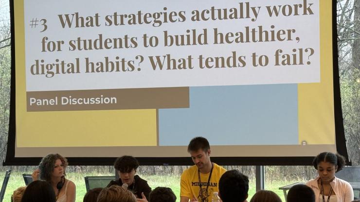 A panel of four young people speak from microphones while seating at a desk, facing a crowd. Behind them, a screen reads: "#3 What strategies actually work for students to build healthier digital habits? What tends to fail?"