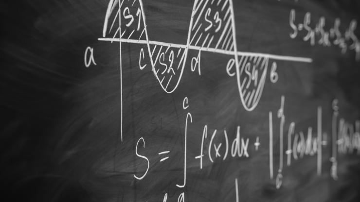 Mathematics function integra graph formulas written in white chalk on a black chalkboard.