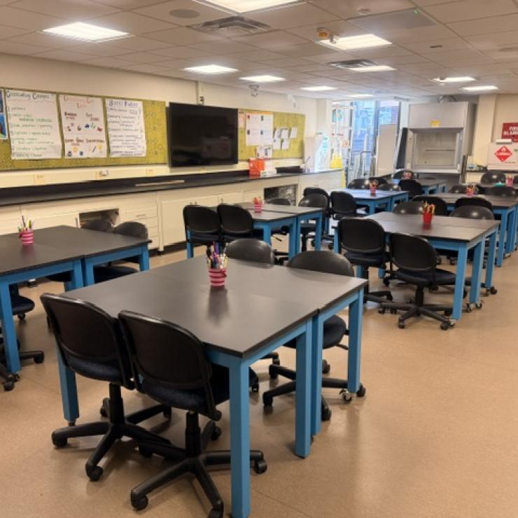 A classroom with desks and chairs, and a bulletin board.