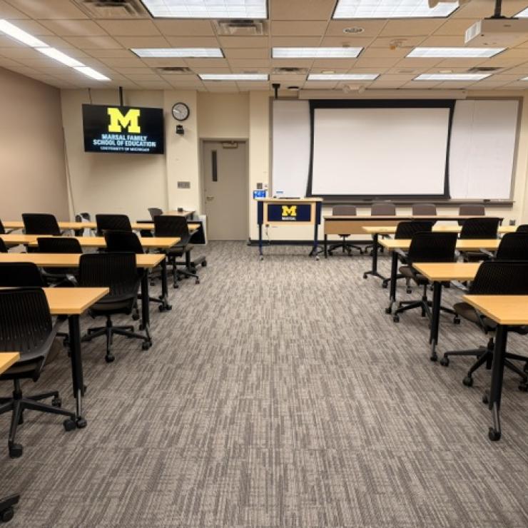 A classroom with desks and chairs facing a whiteboard. 