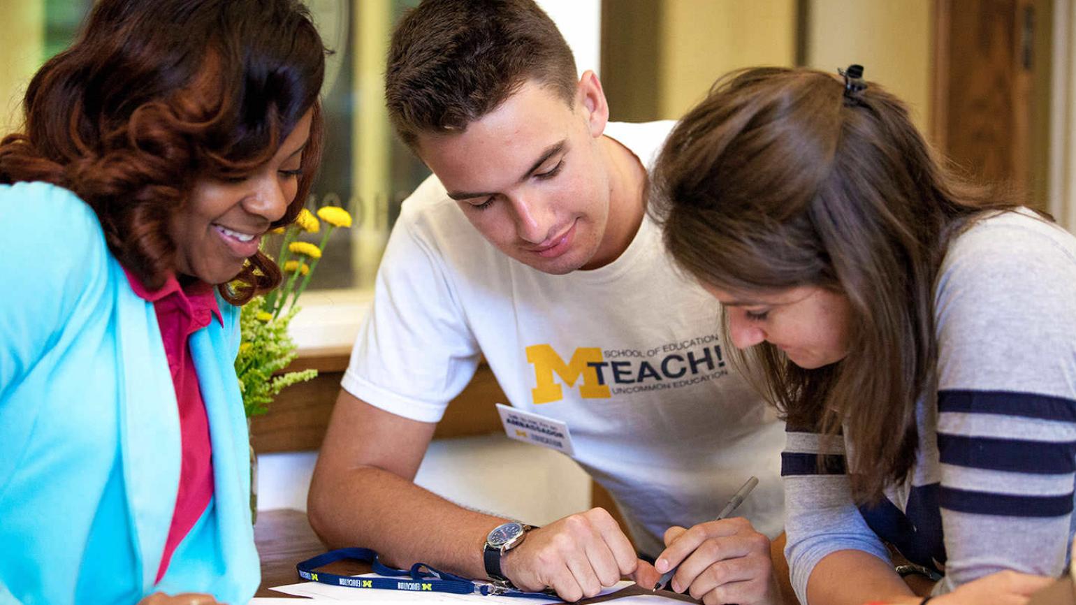 A counselor watches as students fill out a form