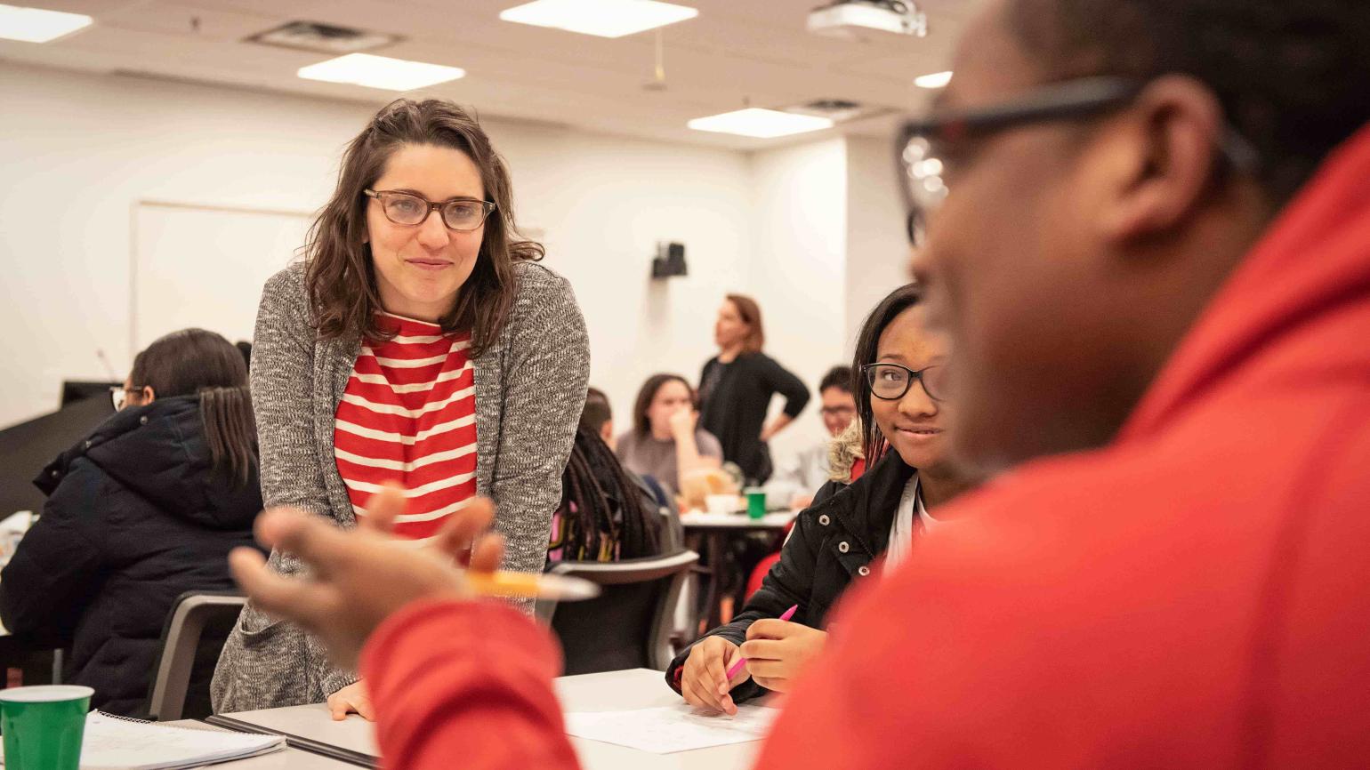 Teacher smiles while listening to speaking student