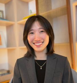 BK Byun is pictured in a gray blazer and black top before a bookcase.