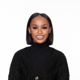 Headshot of Nia Holland, pictured smiling and wearing a black cardigan over a black turtleneck.