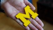 A hand holds a maize block M