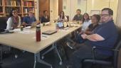 Group of people at a conference table pose for a photo