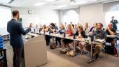CEDER Managing Director Nate Phipps stands at a podium, speaking to room full of event participants