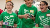 Three young students happily test robotics.