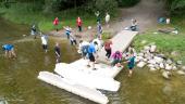 A dozen people scattered around a dock, collecting water samples and looking on.