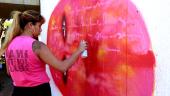 Brazilian graffiti artist Panmela Castro works on a mural project, spray painting a bright pink image.
