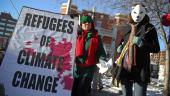 Protesters hold a sign that says "Refugees of climate change."