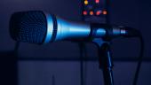 A studio microphone with red and yellow electronic lights in the background.