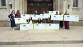 Eleven teachers pose with giant checks from the organization 'Extra Yard for Teachers'. Elizabeth Birr Moje, dean of the Marsal School, stands next to the teachers.