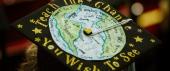 A graduate mortarboard with a hand-drawn depiction of the globe surrounded by the words "Teach the change you wish to see."